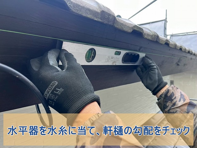 水平器を水糸に当てて軒樋の勾配をチェック